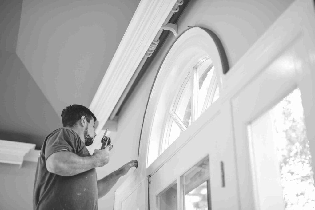A person painting the interior of a house with a roller